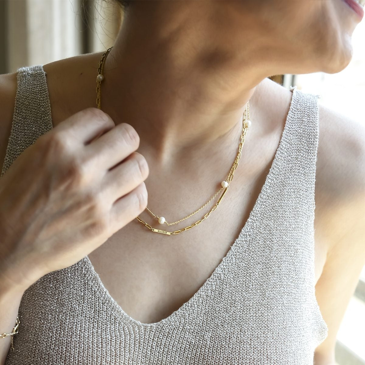 Person wearing a sparkly top and gold necklace with a blurred background