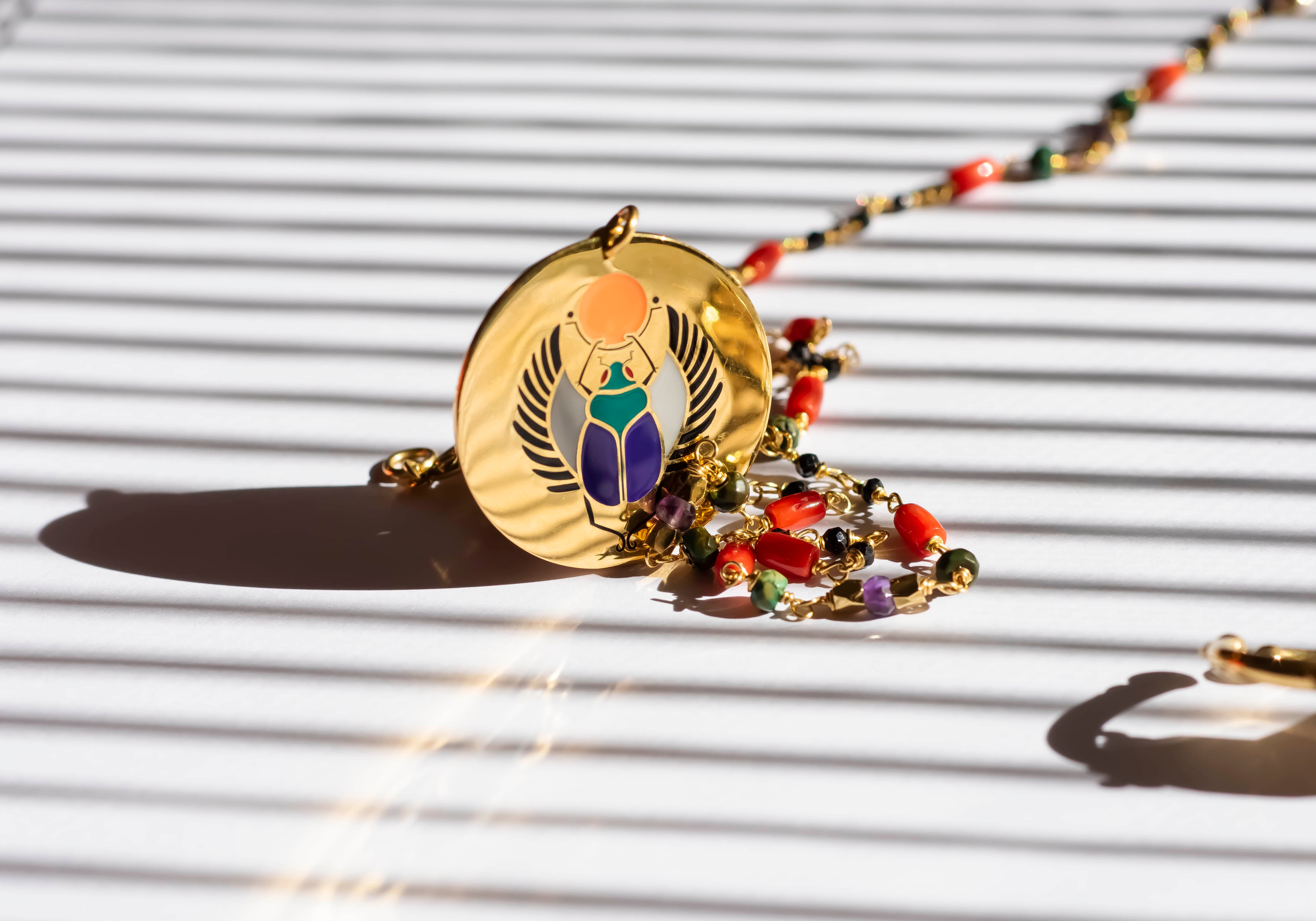 Gold necklace with colorful beads on a textured white surface