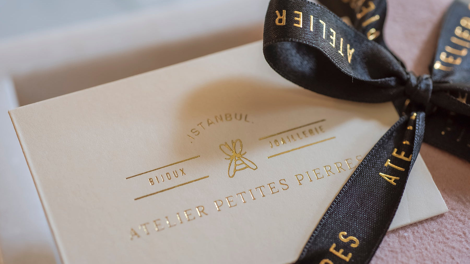 Gift box with a black ribbon featuring 'Atelier Petites Pierres' branding.